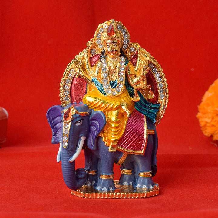 Shani Dev seated majestically on a decorated elephant, symbolizing divine justice and cosmic balance, crafted with detailed features for spiritual decor. India’s Largest Pooja Accessories Brand – www.satvikworld.com